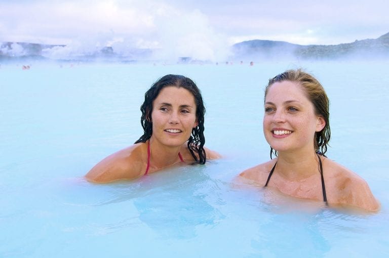 Twee jonge vrouwen genieten van het geothermisch verwarmde water van de Blue Lagoon bij Reykjavik op IJsland