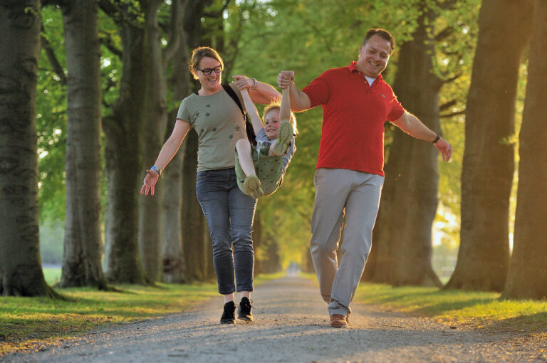 Man en vrouw zwaaien hun zoon in laan met avondlicht