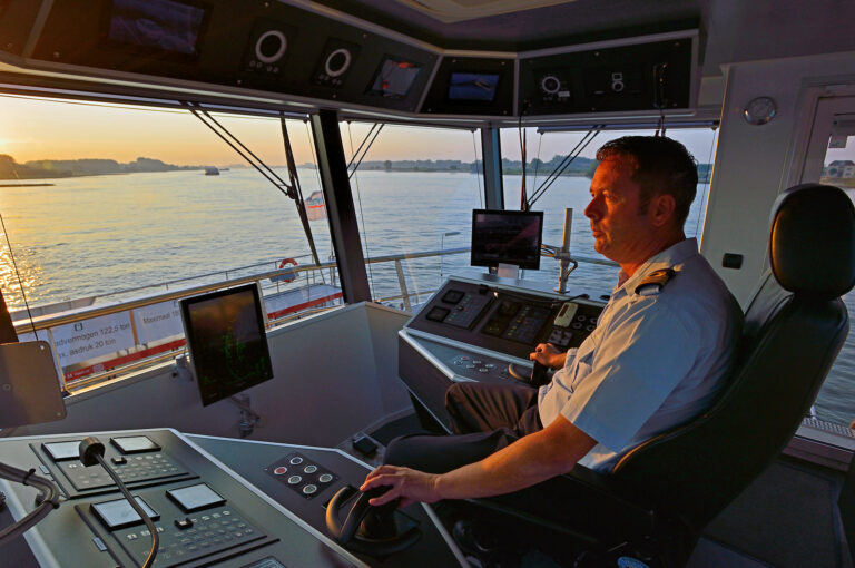 Ferry captain in cabin overlooking the river Waal