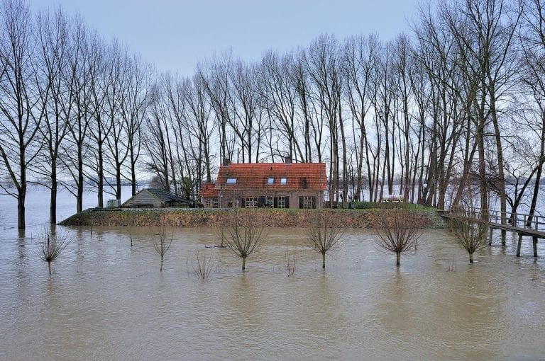 A house is protected by its own dikes from the surrounding high water of the river Waal near Brakel