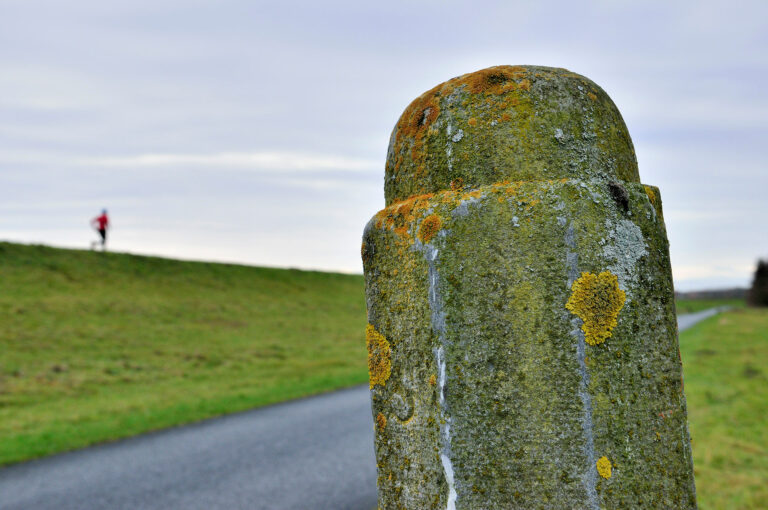 Hoefslagpaal langs de dijk, met hardloper op dijk