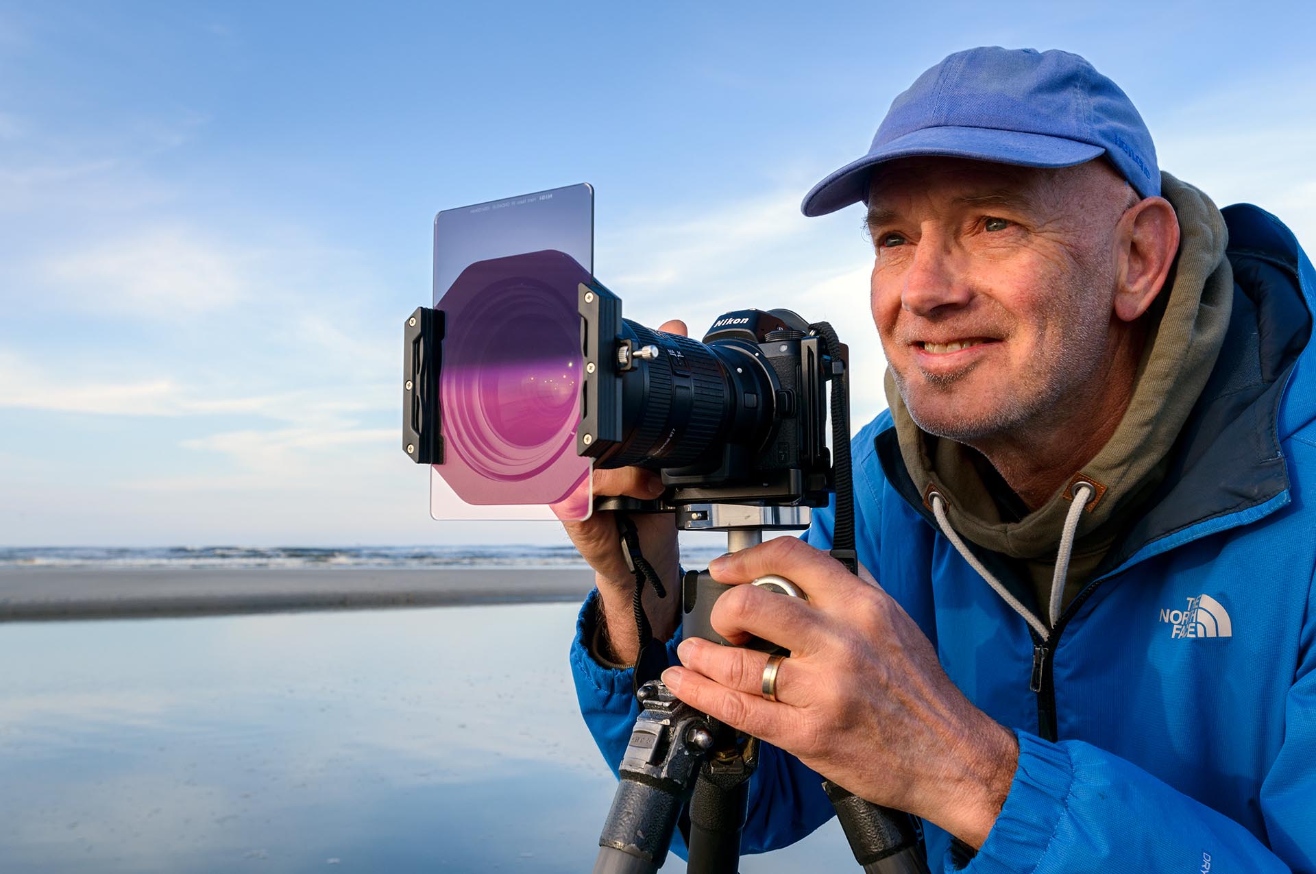 Martin with camera on tripod on beach.