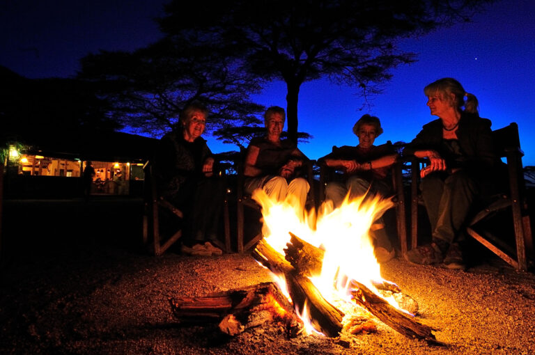 People sit around the campfire of the Ndutu Safari Lodge