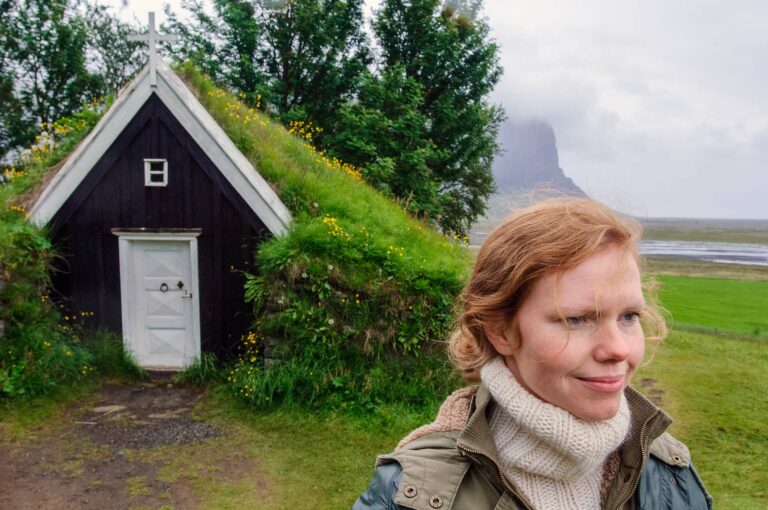 The smallest church of Iceland in Núpsstaður, covered with plants and here with a young Icelandic woman in front