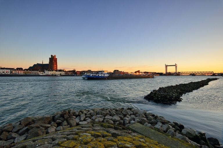 Skyline of Dordrecht at sunset with cargo ship on Nieuwe Merwede and the Grand Church in the old center of the city