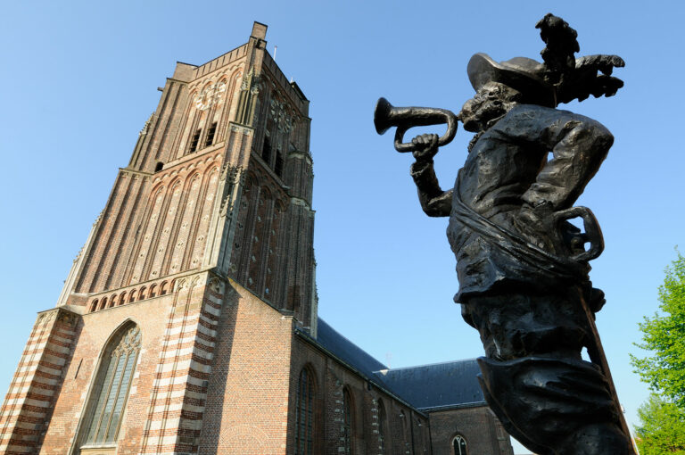 Beeld van Jan Claesen met kerk in achtergrond