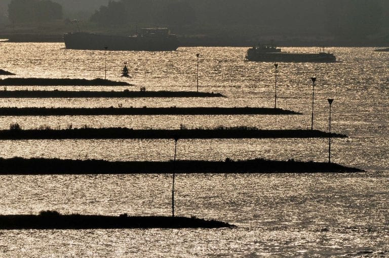 The river Waal with large groynes and cargo ships at Beneden Leeuwen