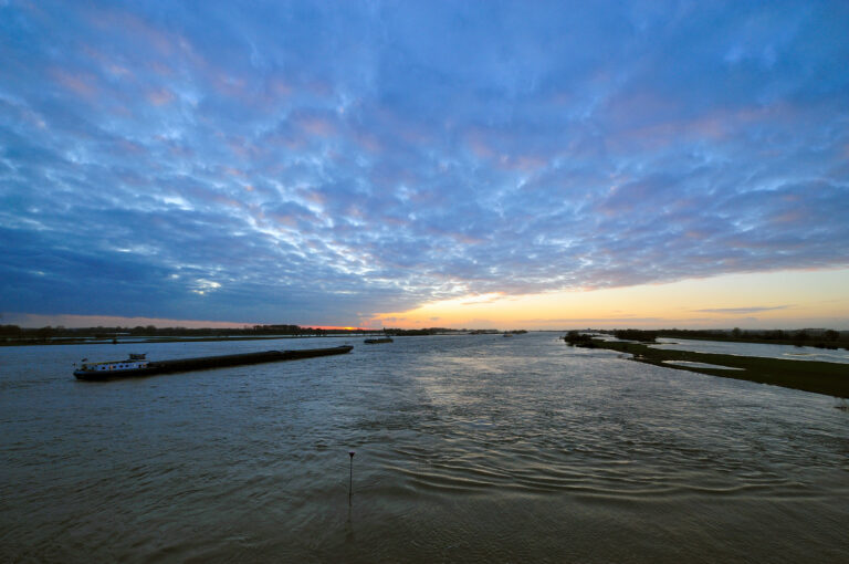 Binnenvaartschip op de Waal bij Ewijk bij zonsondergang.