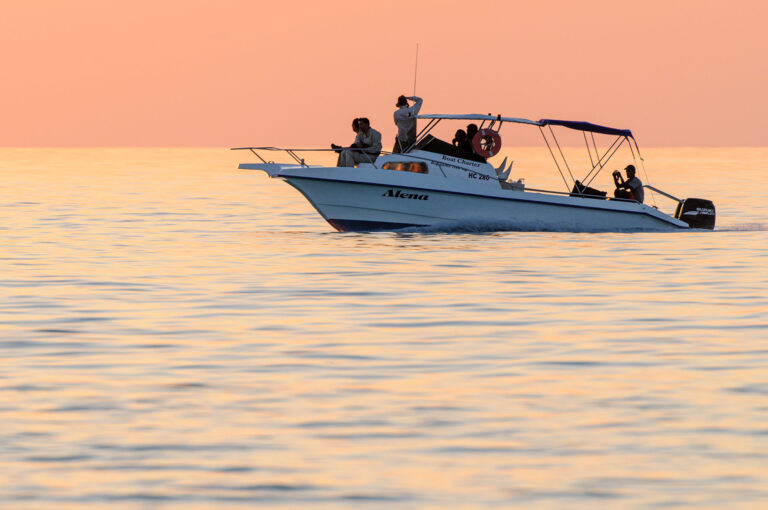 Bootje op zee met fotografen rond zonsondergang