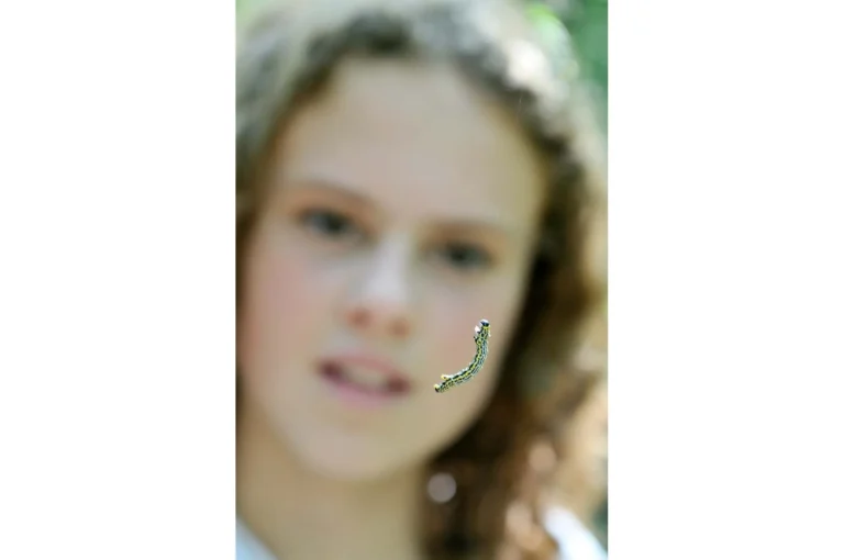 Caterpillar hanging in front of girls face