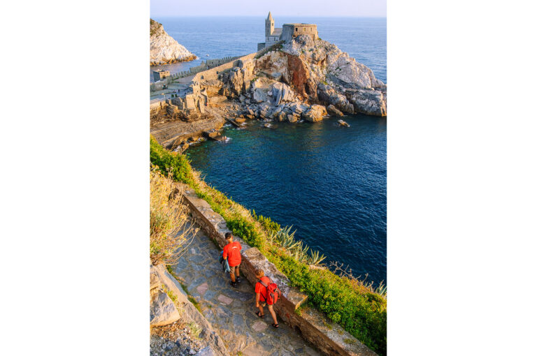 Wandelaars langs de kust bij Portovenere met San Pietro kerk.