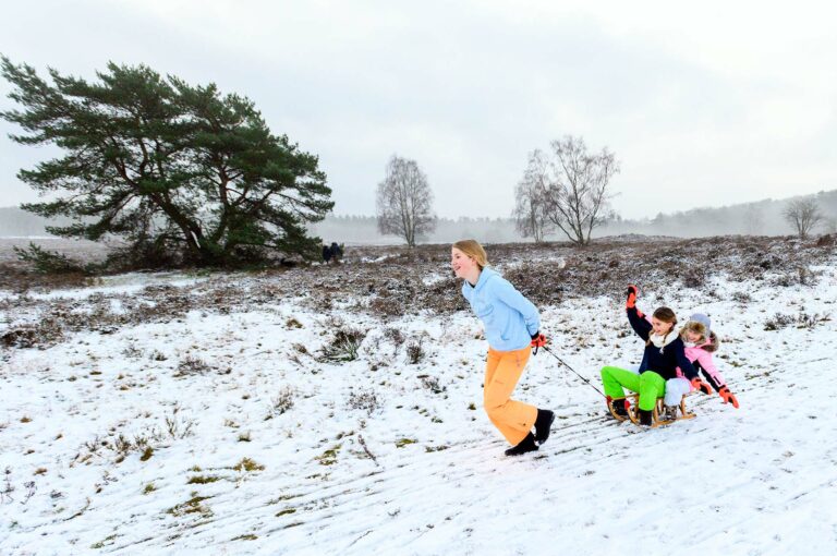 Drie meisjes en een slee in de sneeuw