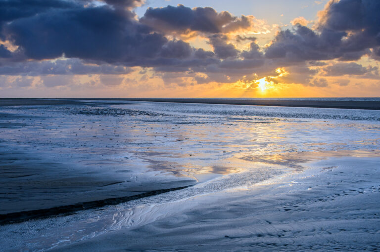 Geul op strand met getijde en ondergaande zon