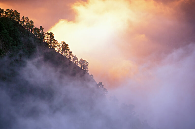 Mountainous landscape with sunlit clouds.