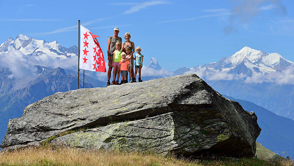 Martin and family in mountains with Swiss flag.