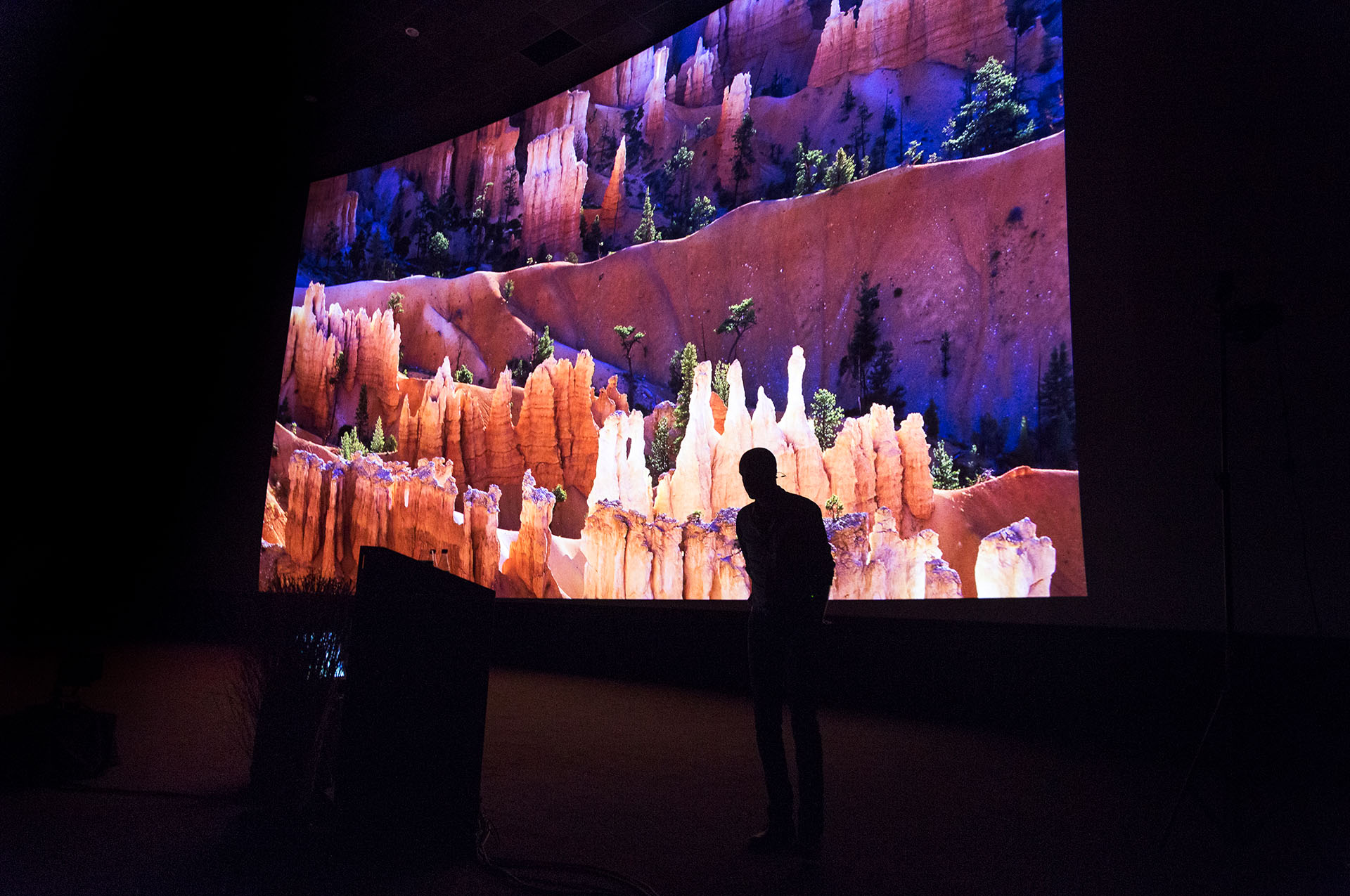 Martin van Lokven gedurende zijn presentatie, met een foto van Bryce Canyon Nationaal Park op het scherm.