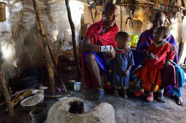 Masaï man and wife with their children in their hut