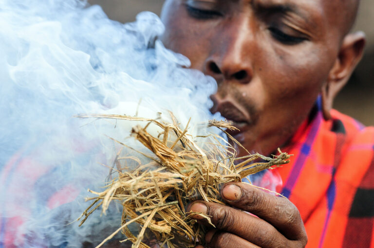 Masaï man maakt vuur aan met stro