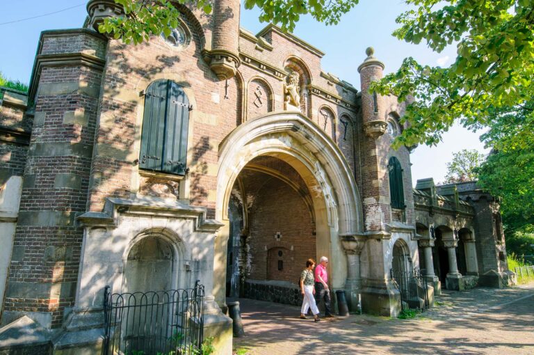 Mensen lopen onder een oude poort in Naarden Vesting.