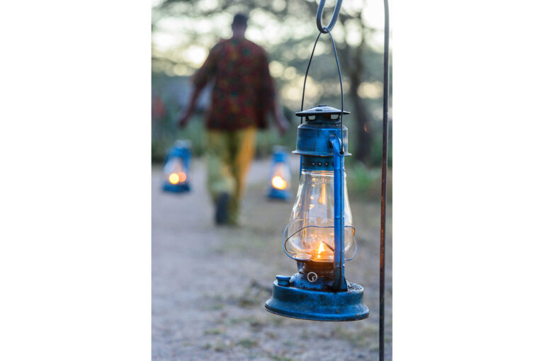 A man hangs lanterns in front of the accommodations at the Ndutu Safari Lodge