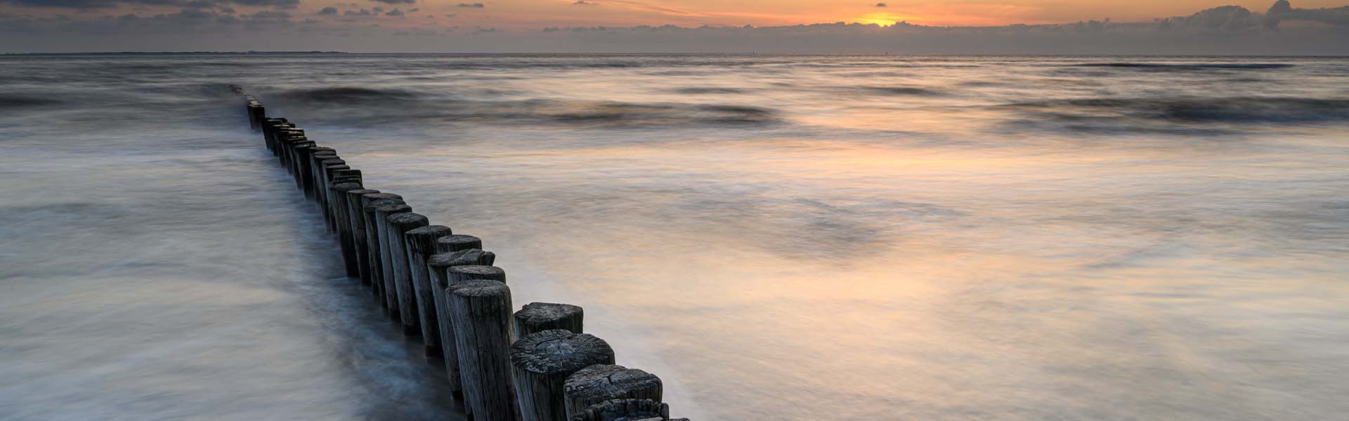 Golfbreker bij zonsondergang, met lange sluitertijd.