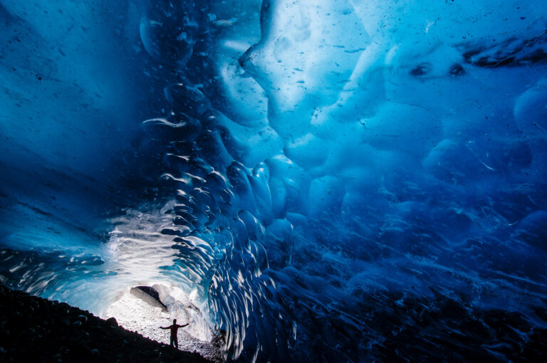 A man is standing in a cave under the Root Glacier