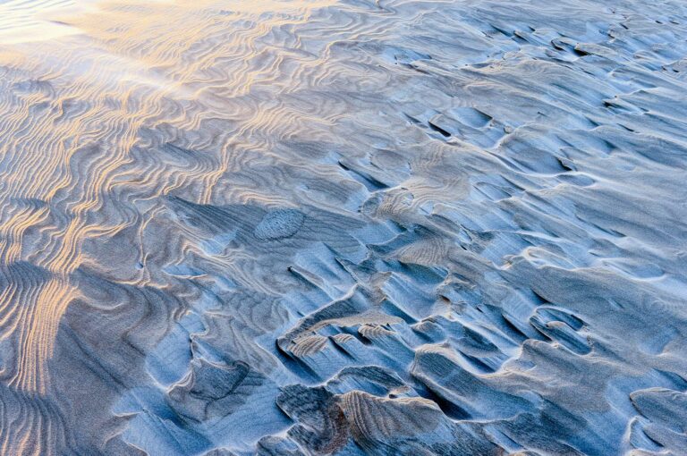 Sand patterns on a beach with most of them in the shadow and some in the last sunlight