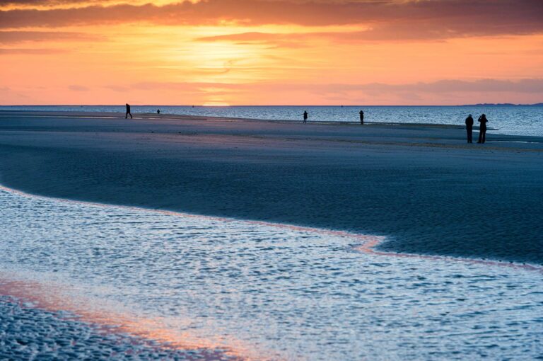 Mensen lopen op het strand van Schiermonnikoog bij zonsondergang