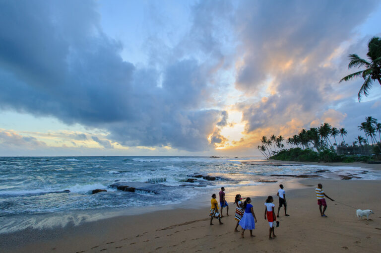 Mensen wandelend op strand met hondje, Galle, Sri Lanka.