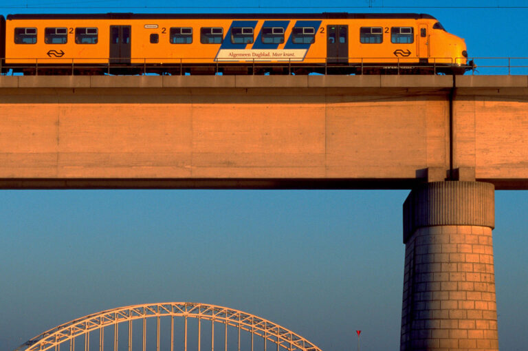 Spoorbrug met trein over de Waal bij Nijmegen bij laatste licht zonsondergang.