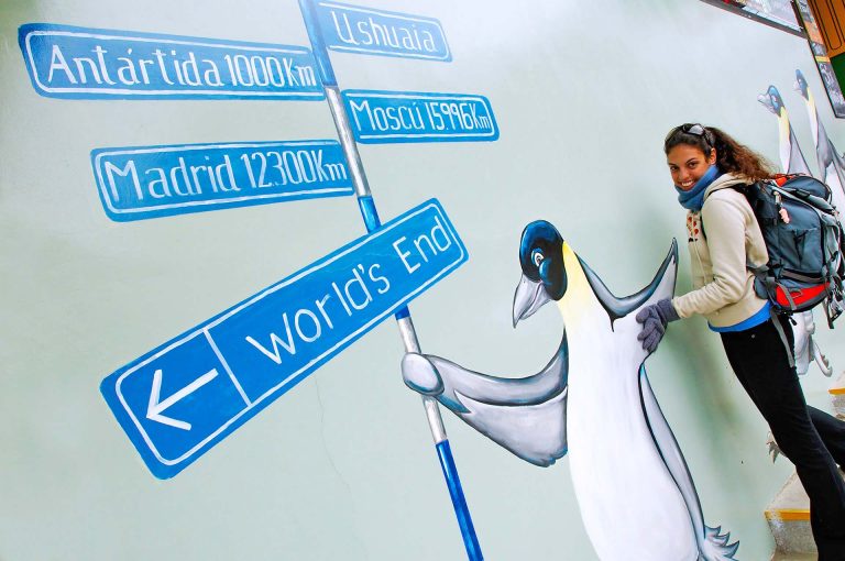 Tourist with penguin wall painting in Ushuaia.