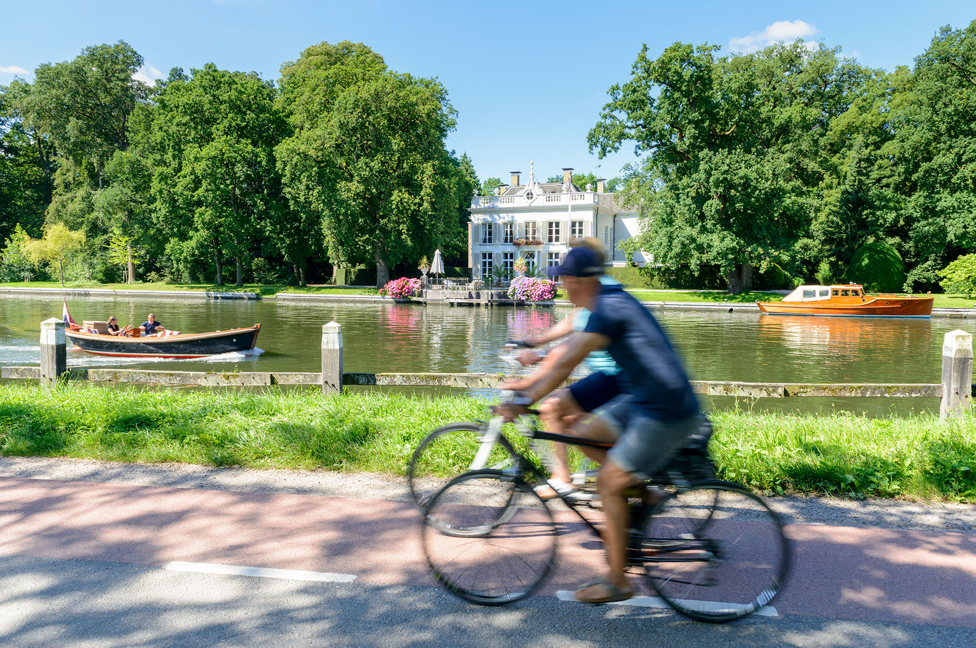 Fietsers langs rivier de Vecht, met bootje en buitenplaats