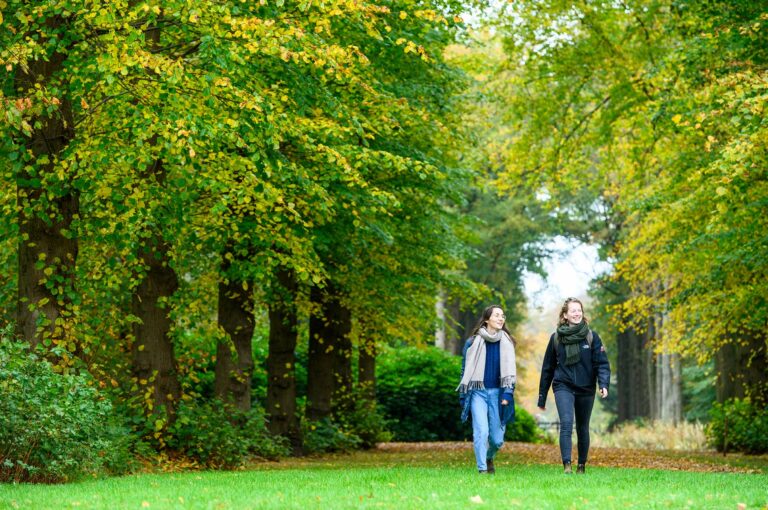 Twee jonge dames wandelen in boslandschap van buitenplaats Boekesteyn bij 's-Graveland.