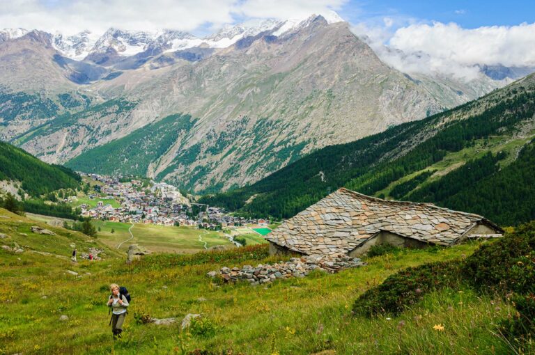 Wandelaar in berglandschap met dorp Saas Fee in achtergrond