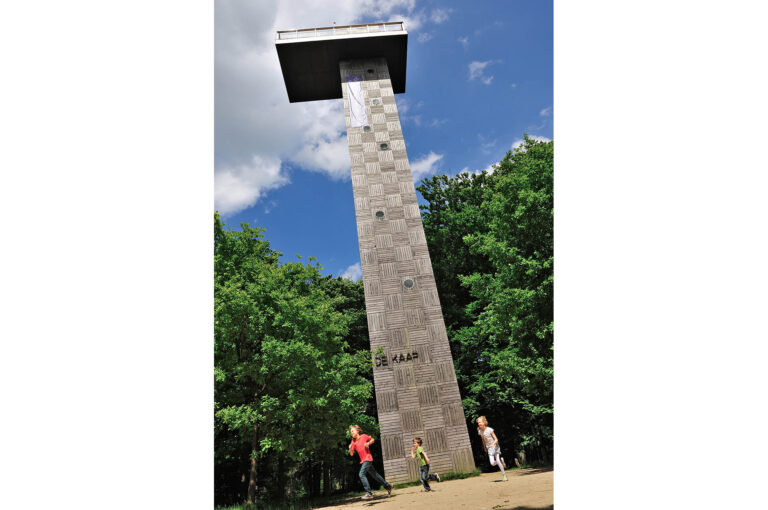 Children running at the base of a watchtower in a forest