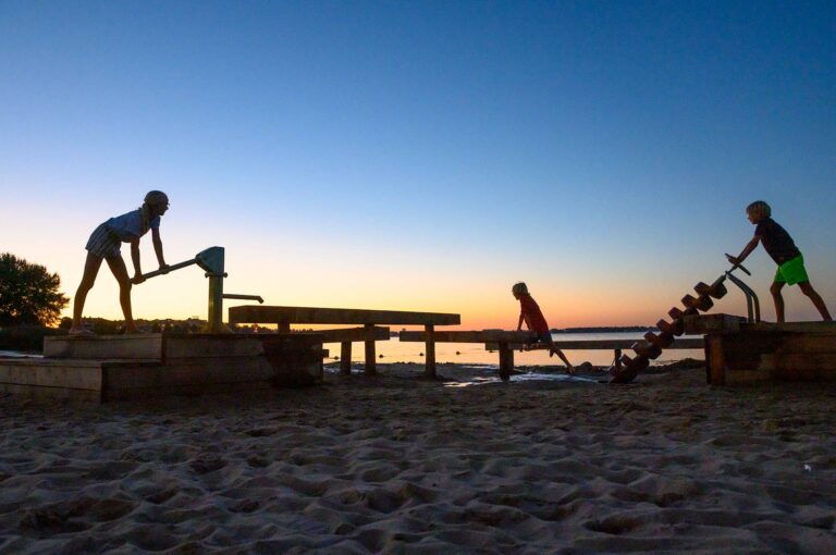 Children playing on water playground, silhouetted against an evening sky