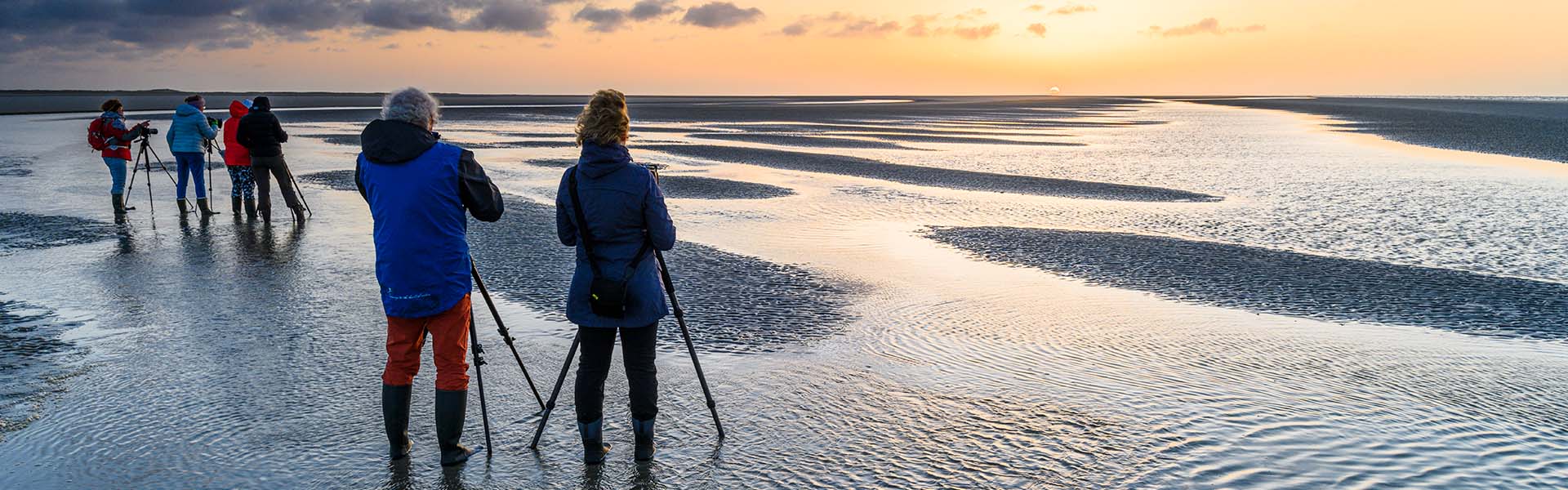 Fotografen op een strand bij zonsondergang.