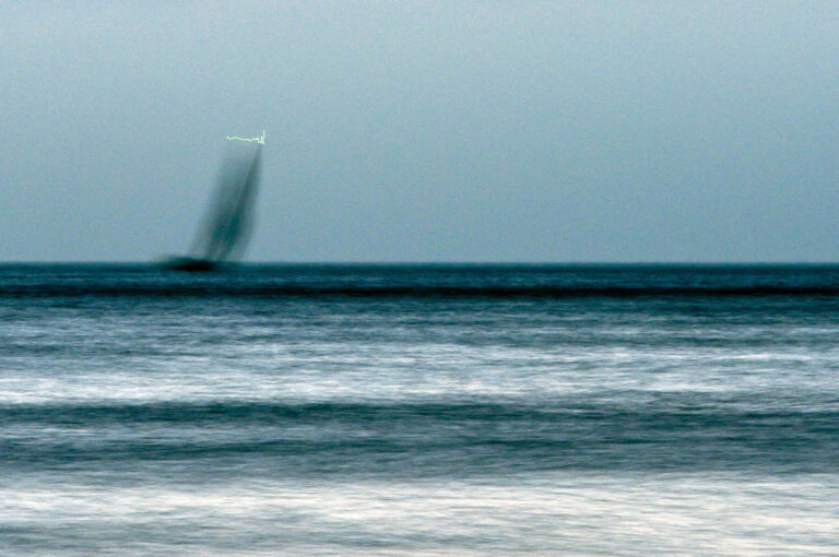 Zeilboot in schemer op zee, met lampje in mast