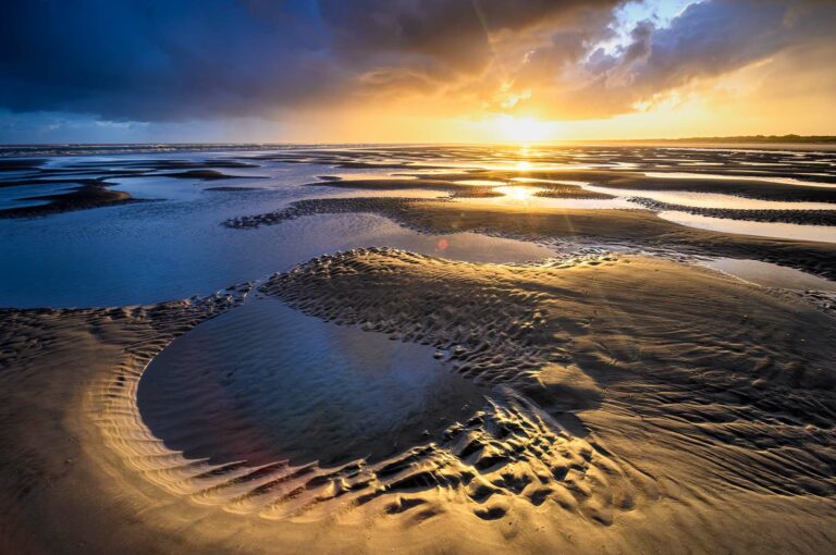 Zonsopkomst boven strand bij eb